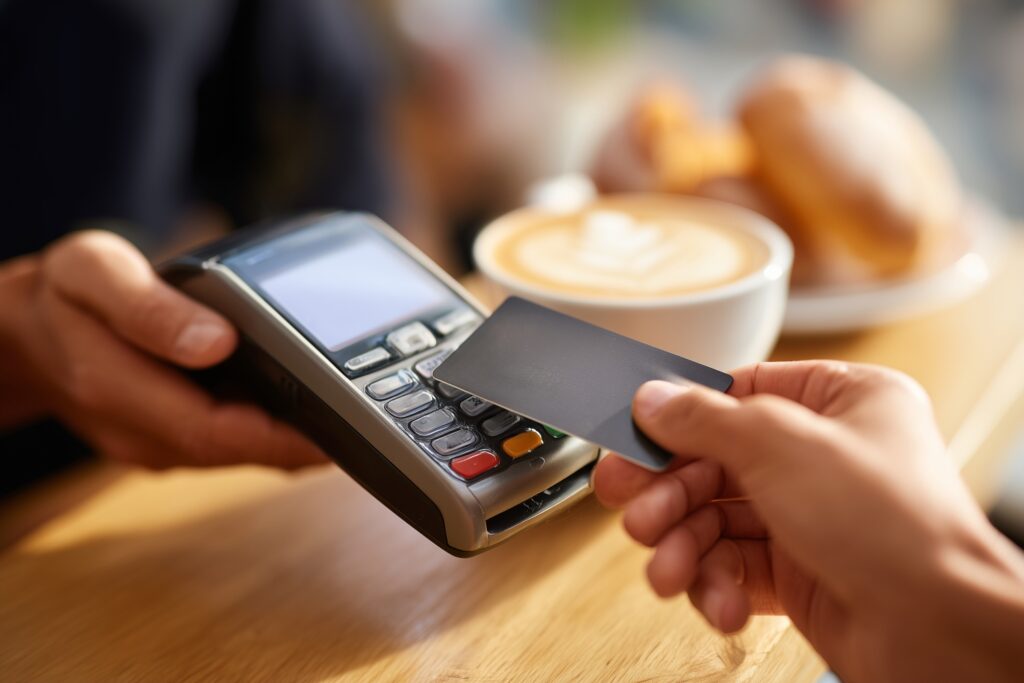 コーヒーの代金をクレジットカードで支払っている人物